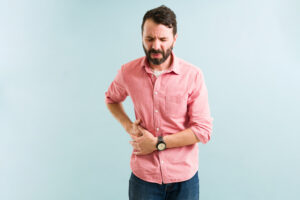 Man clutches his side in pain, prior to a flank hernia repair